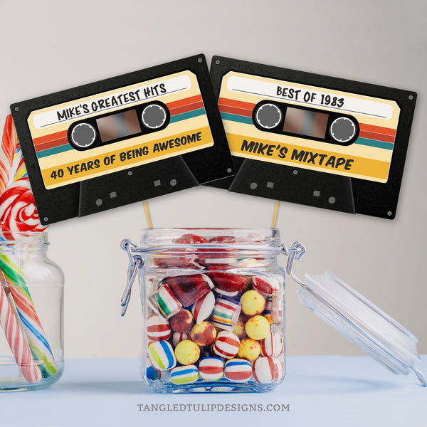 Rewind to the retro vibes with this personalized Cassette Tape Birthday card, to add a touch of vintage flair to your party centerpiece, or use as a topper or label for a groovy mixtape party theme. By Tangled Tulip Designs.