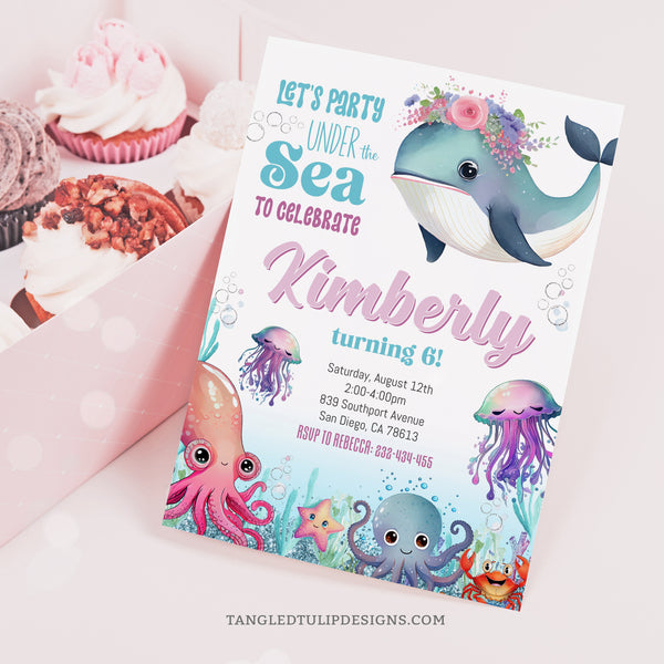Under the Sea Birthday Invitation! This charming design features a cute watercolor whale adorned with flowers on her head, alongside delightful sea creatures such as octopus and jellyfish. With glitter accents adding a touch of sparkle. Tangled Tulip Designs - Birthday Invitations